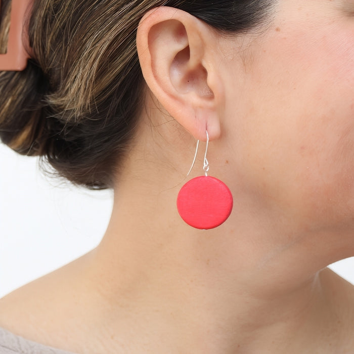 Close-up of a person wearing a red round earring on a white background