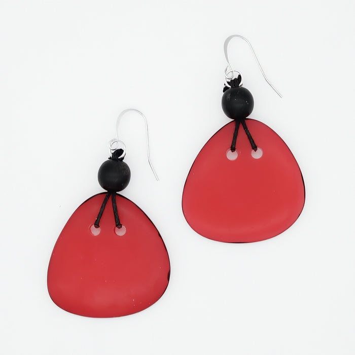 A pair of dangle earrings with large, translucent red teardrop-shaped drops, a small black bead, and silver fishhook wires, shown on a plain white background.