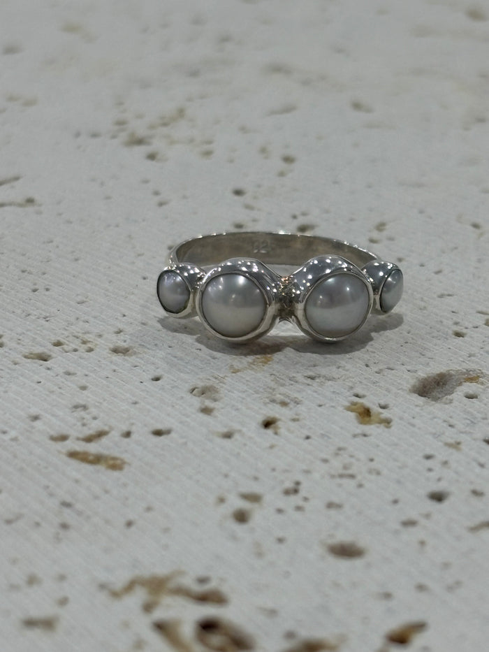 Silver ring with three circular stones on a textured white background