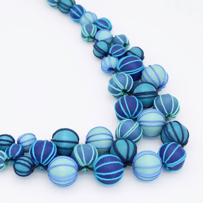 Blue and aqua striped beads on a white background