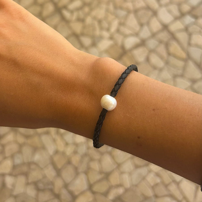 Minimal pearl bracelet on black braided cord worn on wrist – coastal style