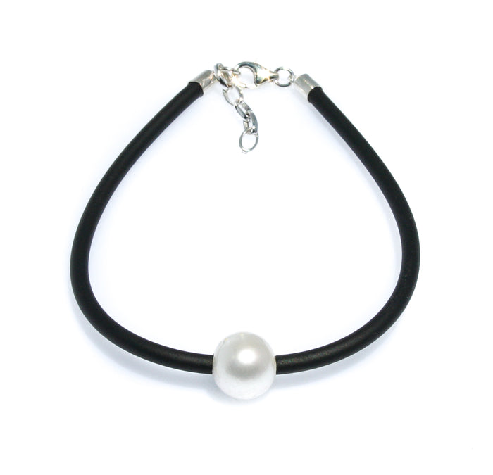 Minimal pearl bracelet on black neoprene cord worn on wrist – coastal style
