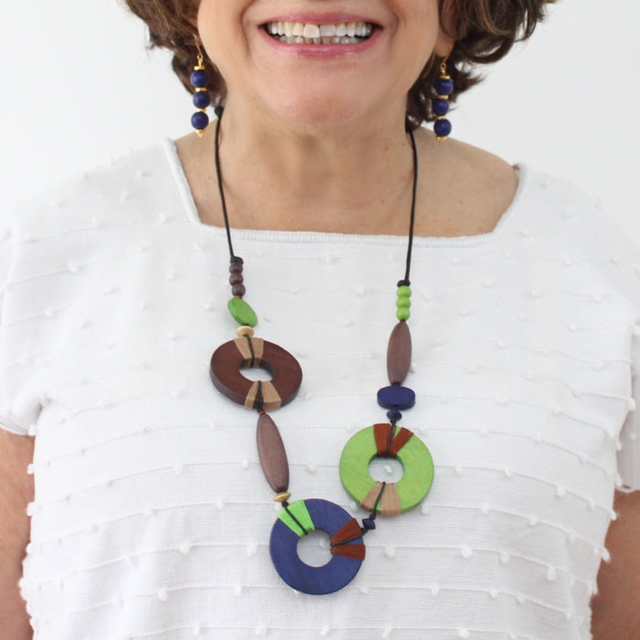 Woman wearing a colorful necklace with wooden and beaded design on a white background