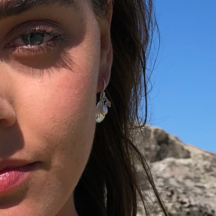 Close-up of a person wearing earrings with a mountainous background