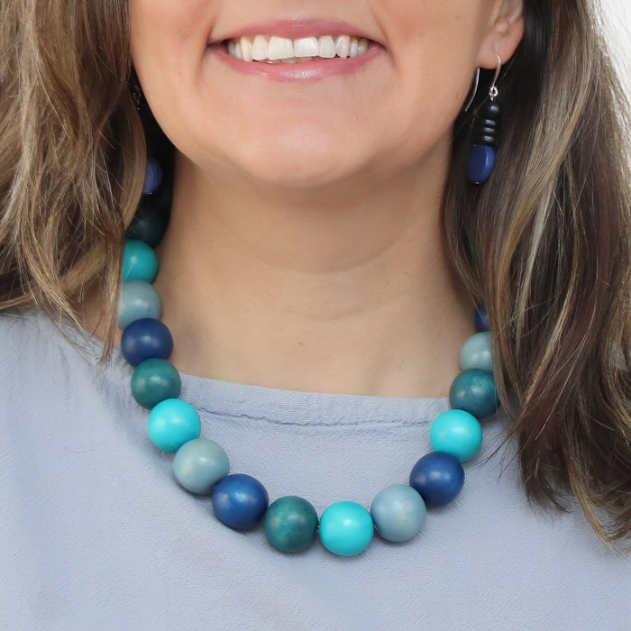 Close-up of a person wearing a blue and green beaded necklace.