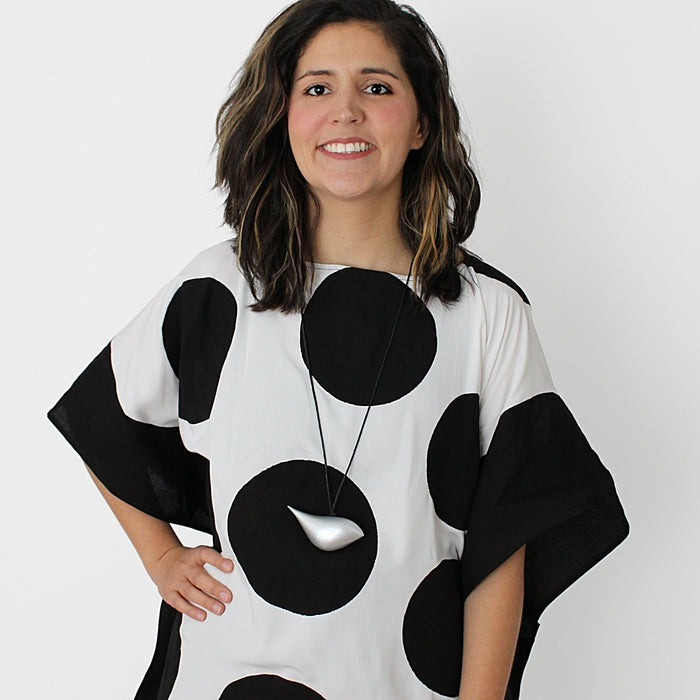 Woman wearing a black and white polka dot dress with a plain background