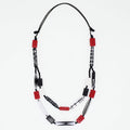 A beaded necklace with red rectangular beads, white beads, and black patterned beads on a black cord, displayed against a plain white background.