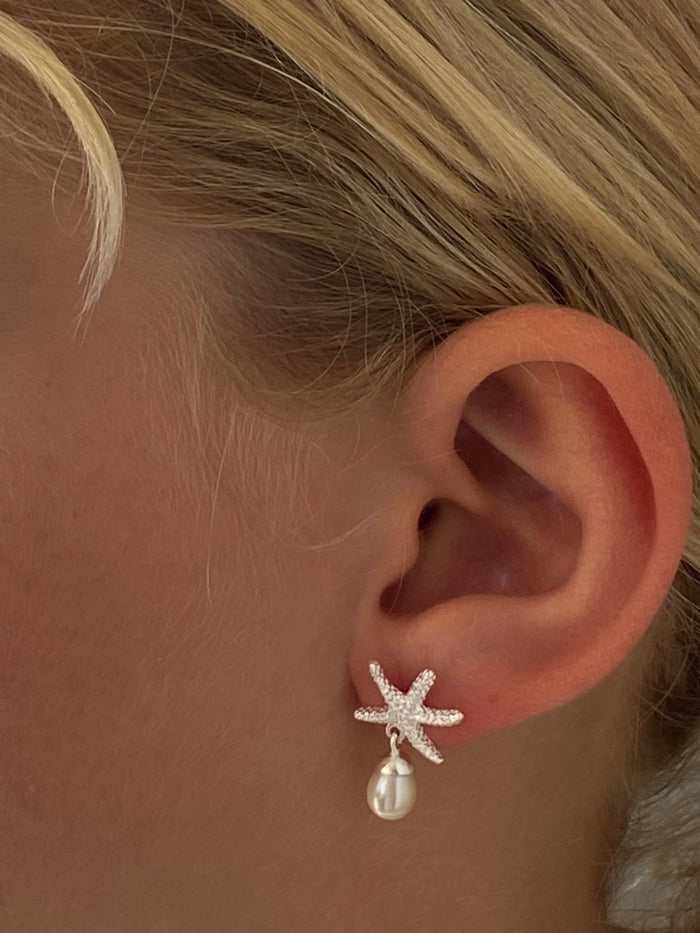 Silver starfish stud earrings featuring a freshwater pearl attached