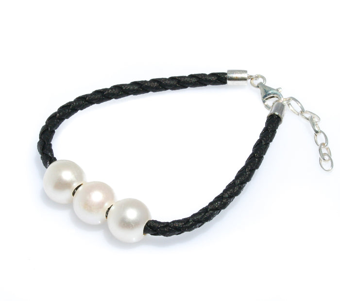 Triple pearl bracelet on black braided cord worn on wrist – coastal style