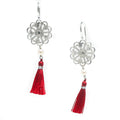 A pair of silver disc earrings with pearl details and red tassel accents