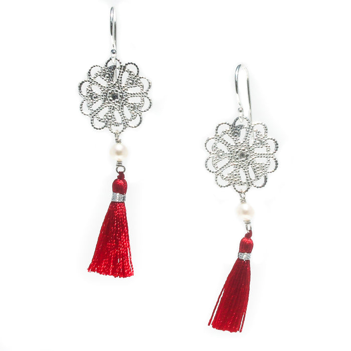 A pair of silver disc earrings with pearl details and red tassel accents