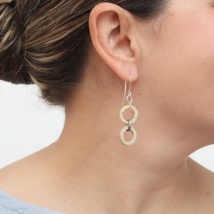 Close-up of a person wearing a silver earring with two interconnected circles.