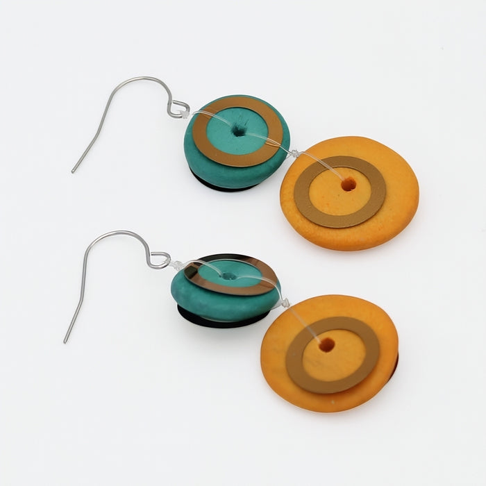 Pair of earrings with circular designs in orange, brown, and teal on a white background