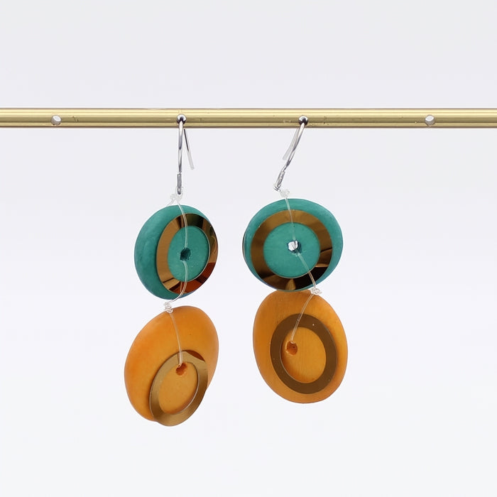 Pair of earrings with circular design in green and orange on a white background