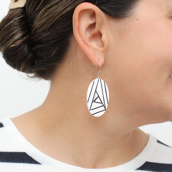 Close-up of a person wearing a black and white geometric earrings.