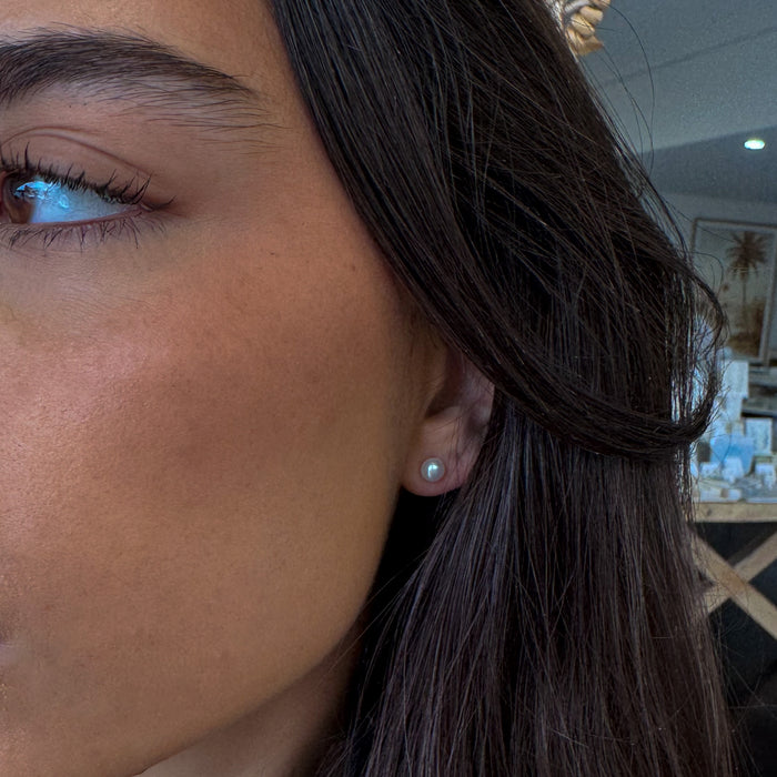 Close-up of a person's ear with an earring, blurred indoor background