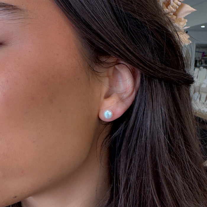 Close-up of a person wearing a light blue earring with a blurred background