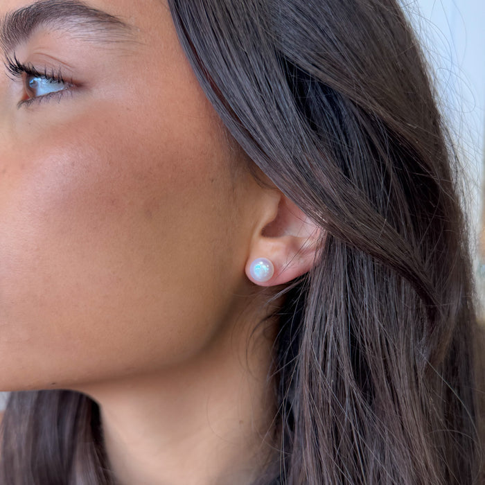 Close-up of a woman's ear wearing a small earring with a blurred background