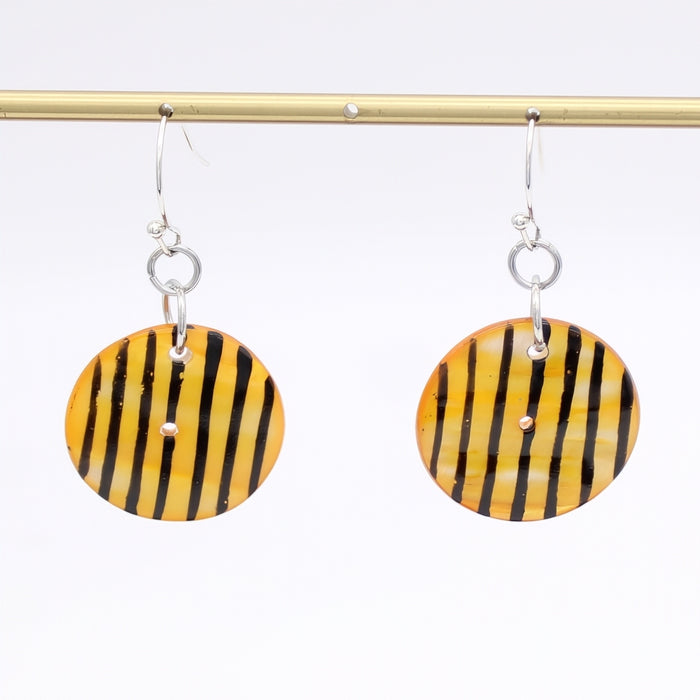 Yellow and black striped earrings on a gold rod against a white background