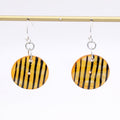 Yellow and black striped earrings on a gold rod against a white background