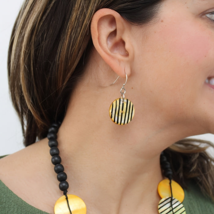 Close-up of a person wearing yellow and black striped earrings with a green top.