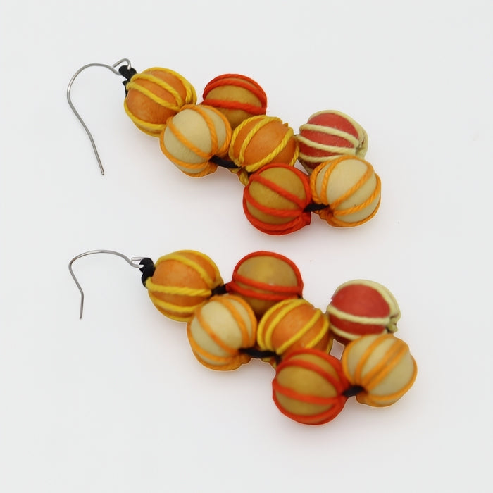 Pair of beaded earrings with orange and yellow striped beads on a white background