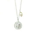 A silver necklace with a round pendant featuring the Scorpio zodiac symbol and a freshwater pearl charm attached to the chain.