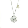 A silver necklace featuring a Taurus bull pendant with a lustrous pearl attached to the top.